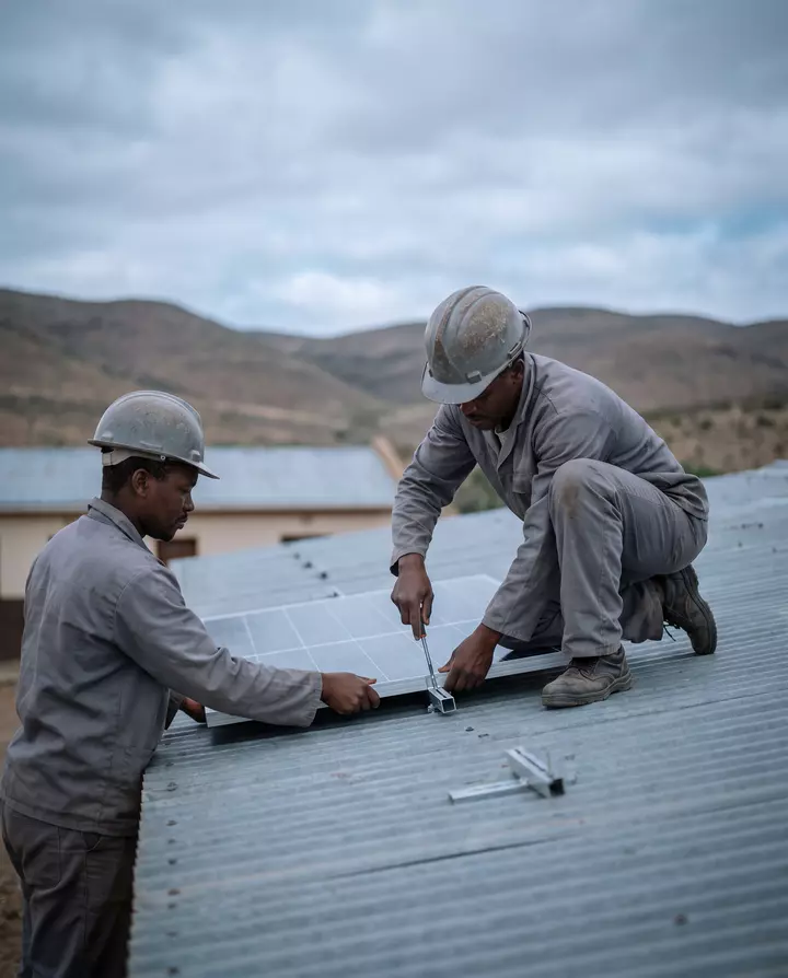 Solar installers fitting panels to a rural school roof