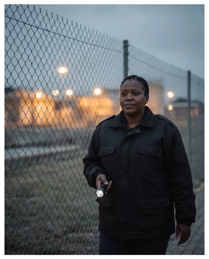 A security officer on night patrol at a water works fence